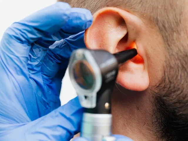 Orvos otoszkóppal vizsgálja a páciens fülét klinikai környezetben